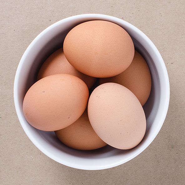 four eggs in a white bowl on a table