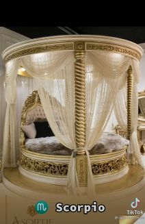 an ornate gold bed with white drapes on it's headboard and foot board