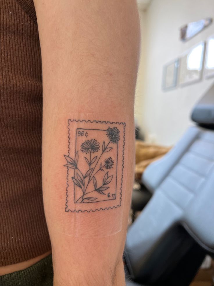 Photo of a tattoo that is inspired by a postage stamp. Flower Stamp Tattoo Ideas, Small Stamp Tattoo Ideas, Peony Stamp Tattoo, Honeysuckle Stamp Tattoo, Hollyhocks Flowers Tattoo, Flower Polaroid Tattoo, Wildflower Stamp Tattoo, Flowers In A Frame Tattoo, Post Stamp Flower Tattoo