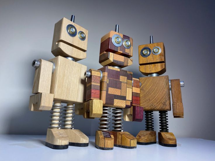 three wooden toy robots standing next to each other