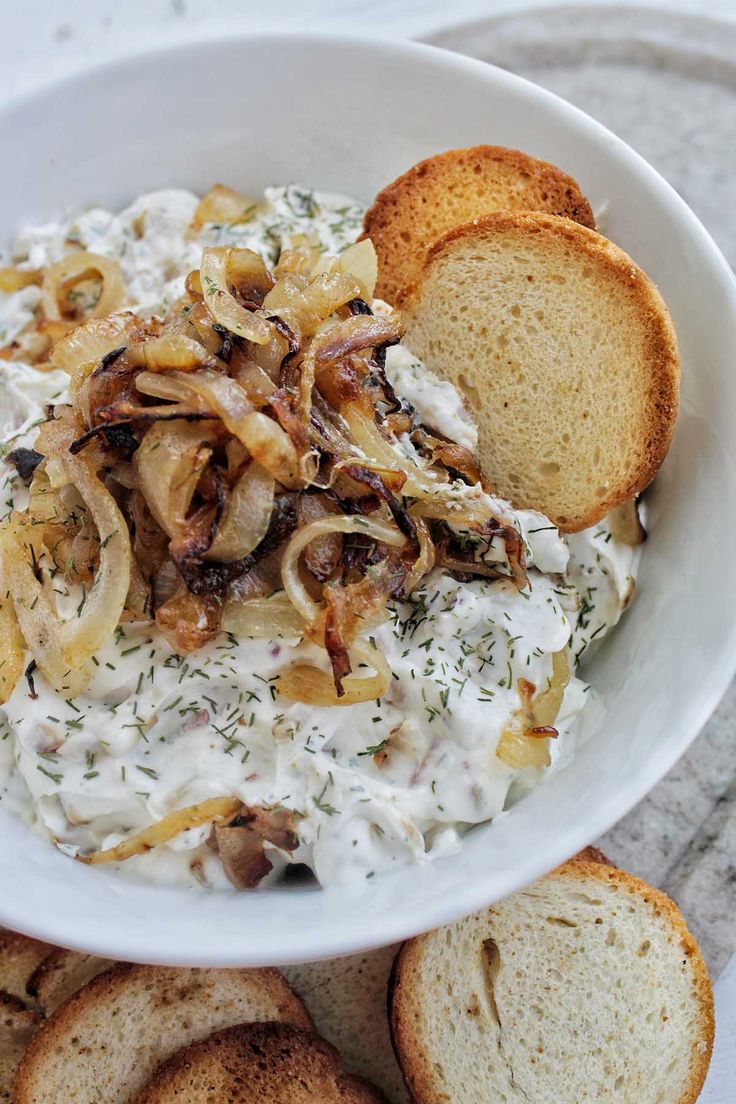 a white bowl filled with food next to slices of bread