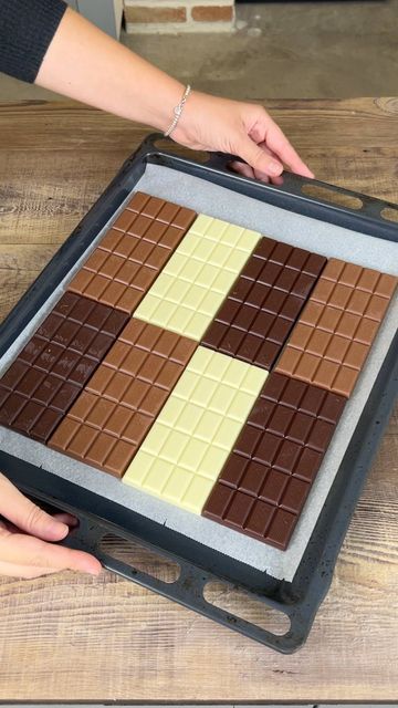 a person is holding a tray with chocolate squares on it and placing them in the pan