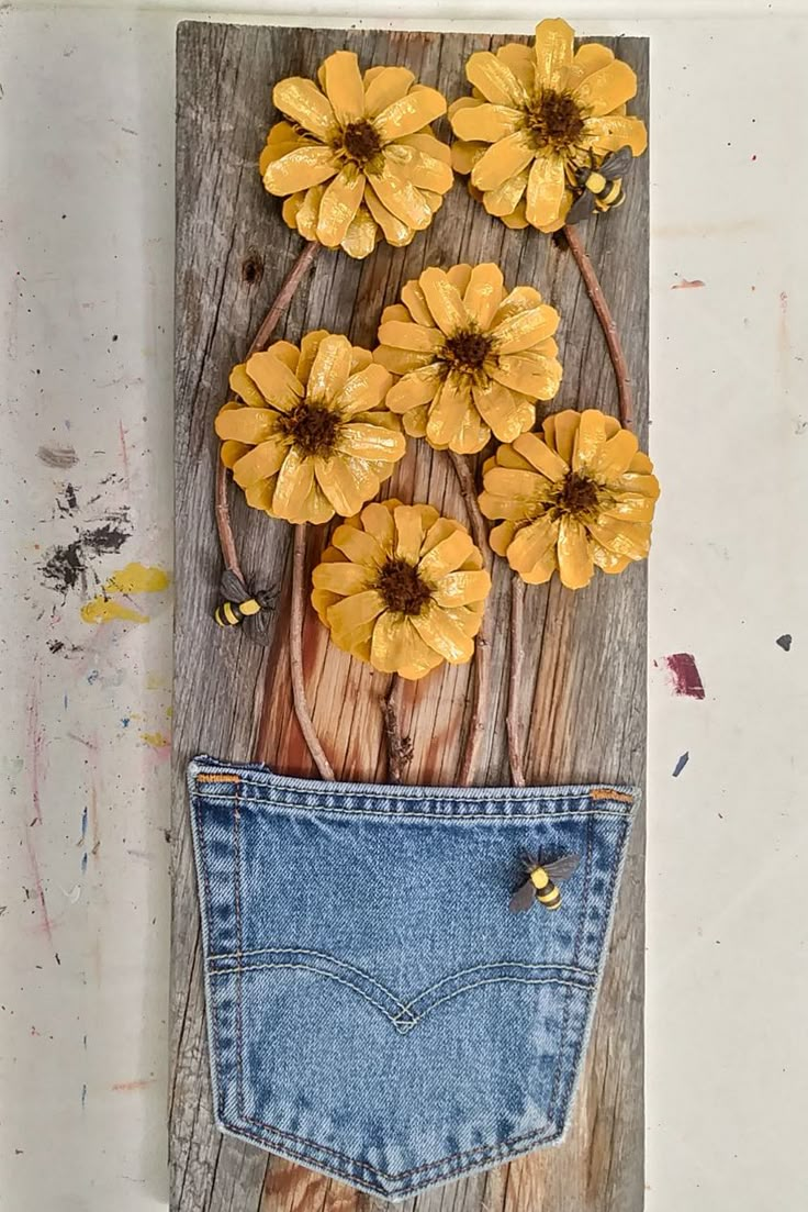 some yellow flowers are in the back pocket of a blue jean skirt on a wooden board