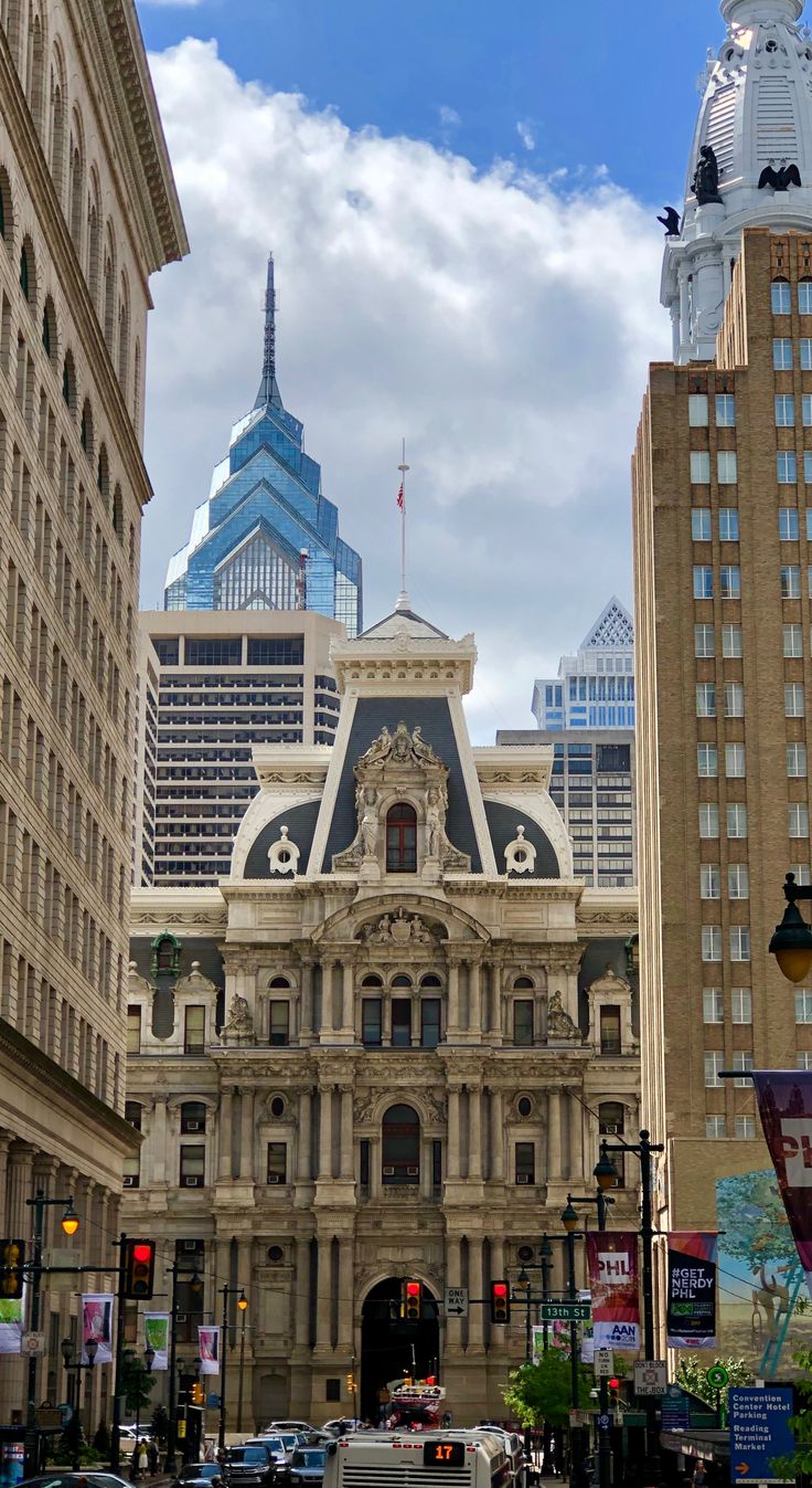 an old building in the middle of a city with tall buildings on both sides and cars driving down the street