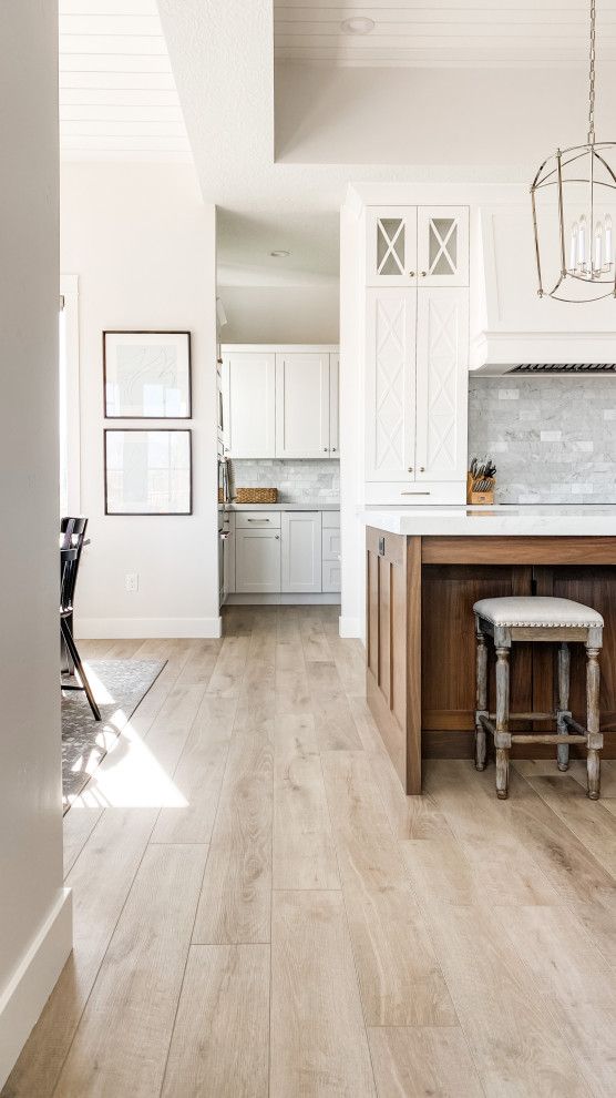 an open kitchen with white cabinets and wood flooring, as well as a dining room table