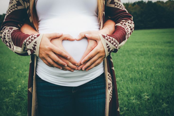 a pregnant woman making a heart shape with her hands