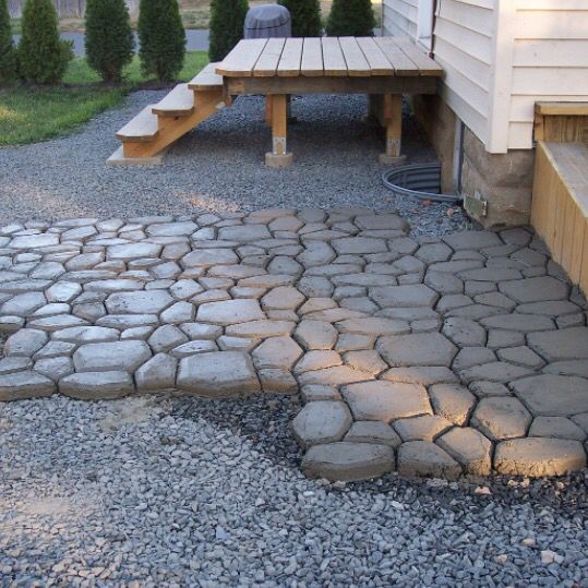 a stone patio with benches in the background and gravel on the ground next to it