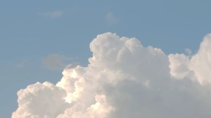 the plane is flying high in the sky with clouds behind it and blue skies above