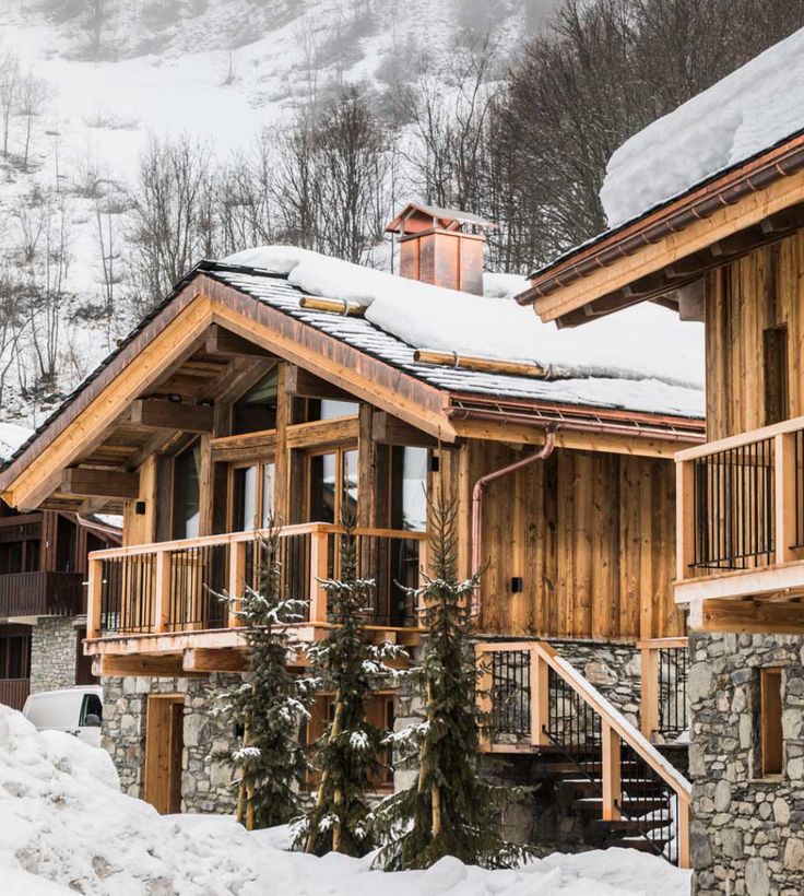 a wooden house with snow on the roof and stairs leading up to it's second story