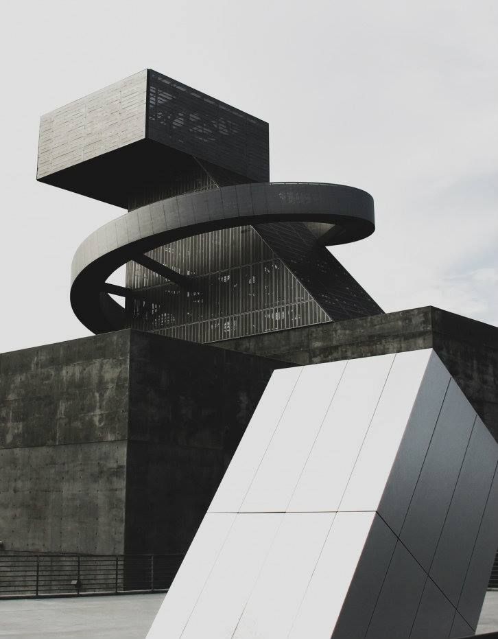 a skateboarder is doing a trick in front of a building with an unusual design