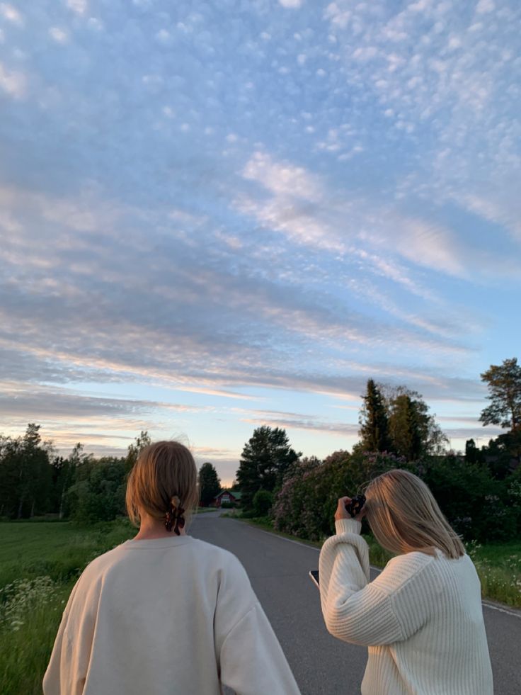 two people are walking down the road taking pictures