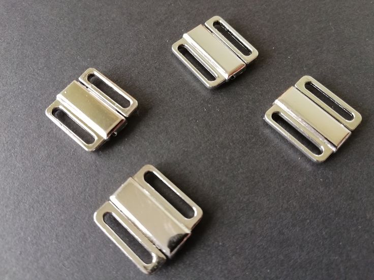 four metal buckles on a black surface