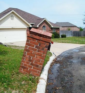 a brick fire hydrant sitting in the middle of a driveway next to a house