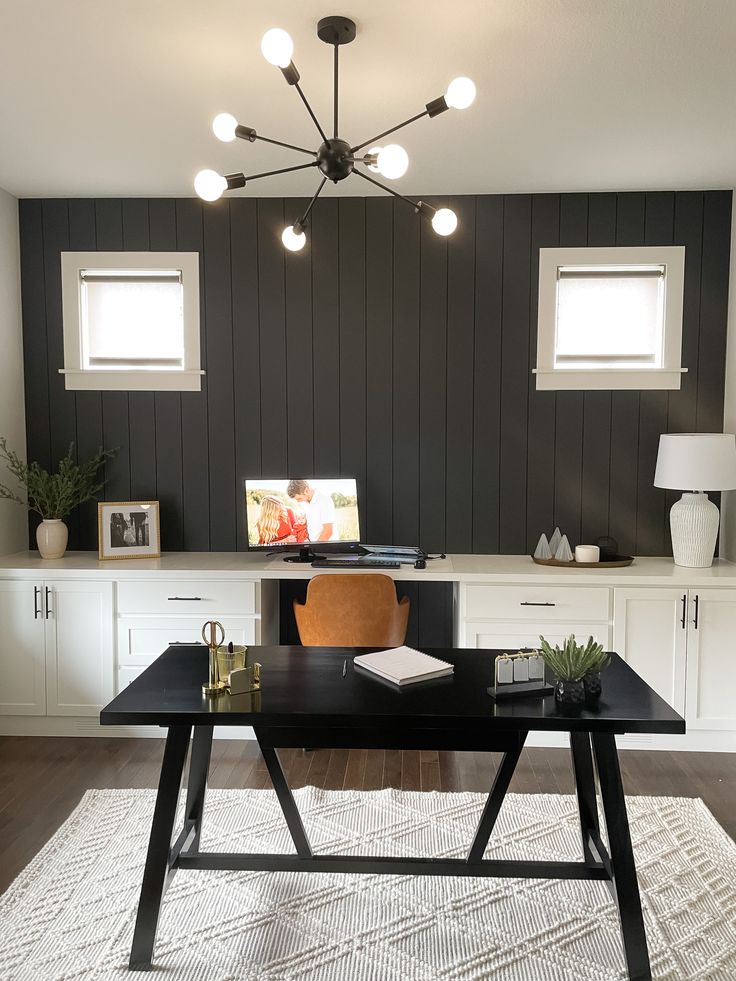 a black table sitting on top of a rug in front of a white desk and cabinets