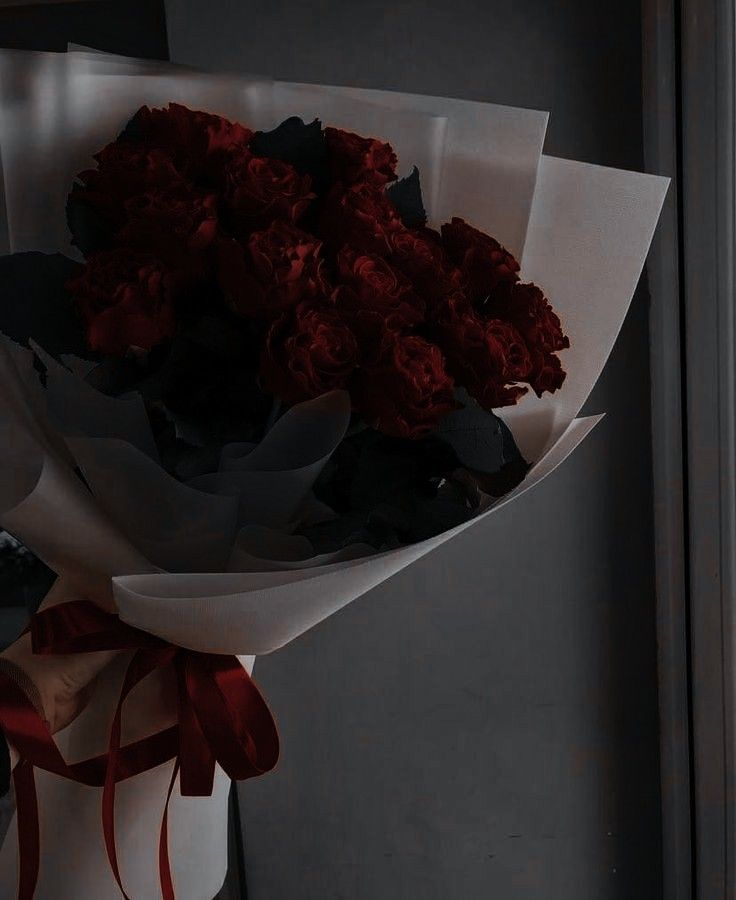 a bouquet of red roses wrapped in white paper