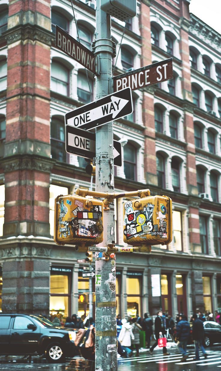 the street signs are clearly visible for everyone to see on this busy city street corner