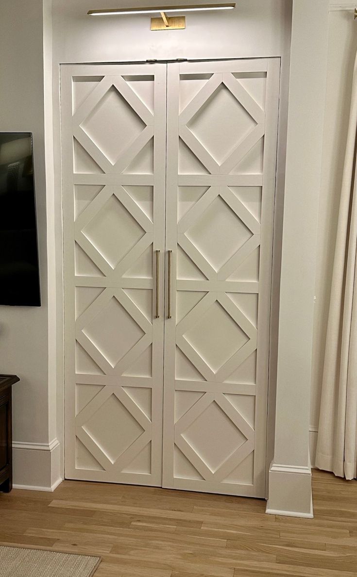 a large white closet with two doors and a television on the wall in front of it