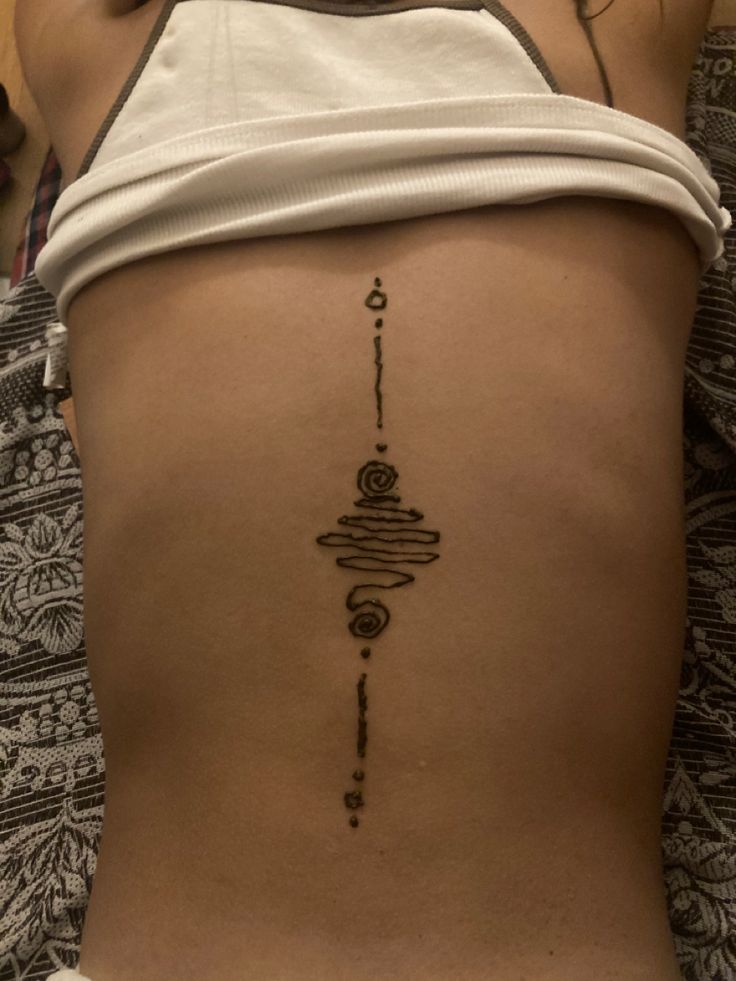 the back of a woman's stomach with a tattoo design on her left side