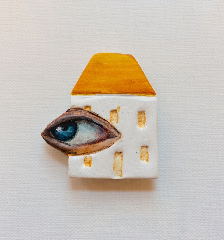 an eye is shown in the center of a small white object with gold accents on it