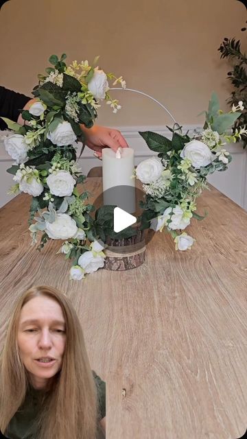 a woman sitting at a table with a candle and flowers around her head, in front of the camera