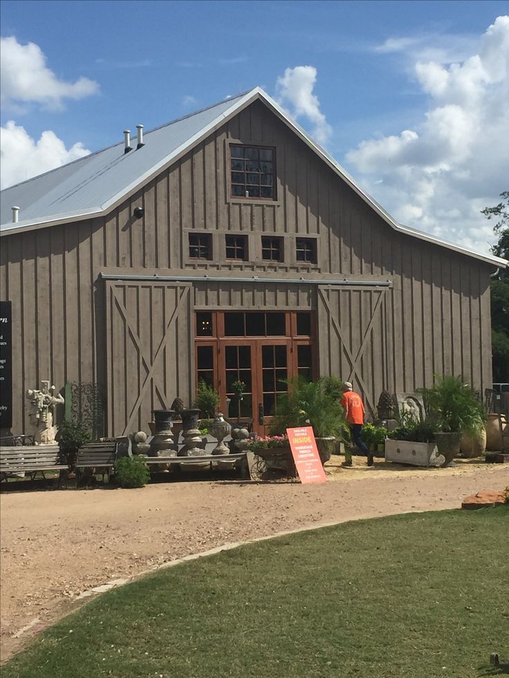 a large barn with lots of potted plants on the front and side of it