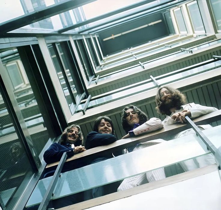 the beatles are sitting on a bench in front of a window with their heads down