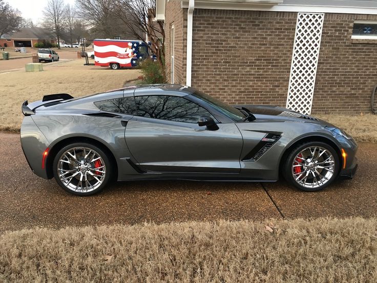 a gray sports car parked in front of a brick building with american flag on it