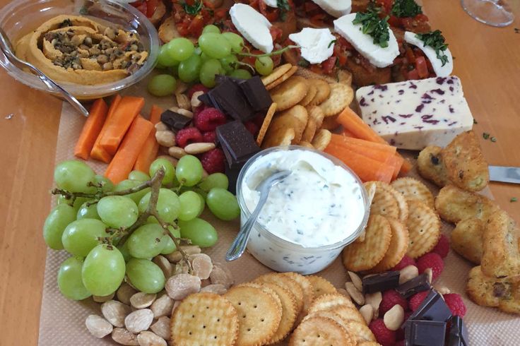 an assortment of cheeses, crackers and fruit on a table