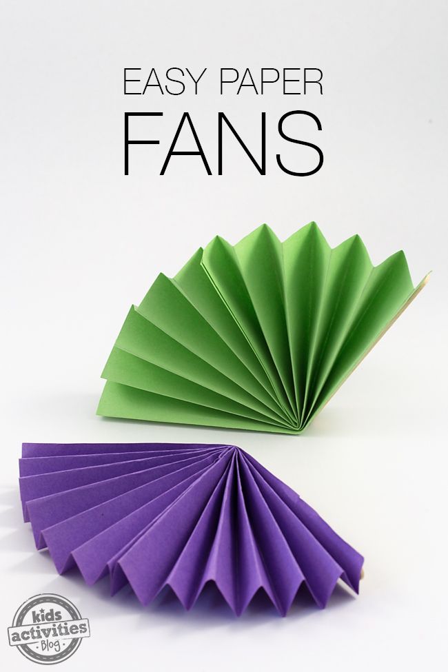 two origami fans sitting next to each other on a white surface, one is green and the other is purple