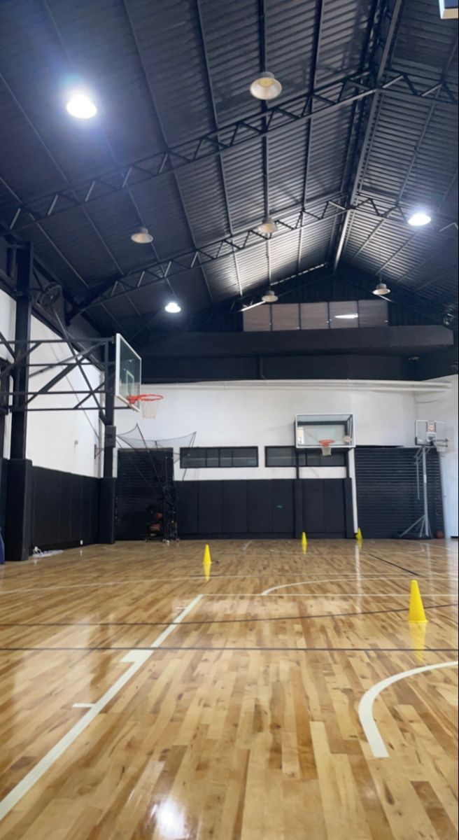 an indoor basketball court with hard wood flooring and white lines on the sidelines