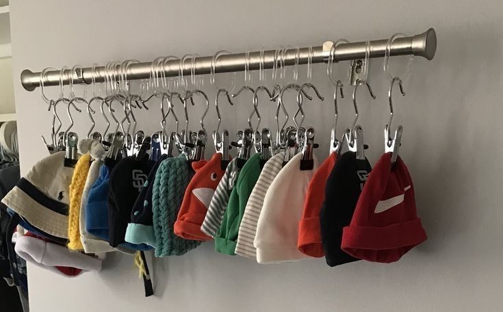 there are many hats hanging on the hooks in this room, and one is wearing a hat