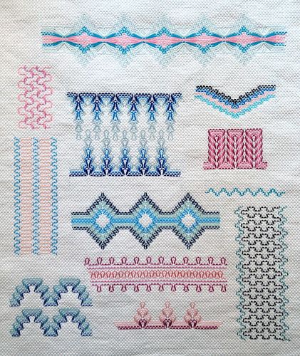 an embroidered sample of different designs on white fabric with blue and pink accents, including lines