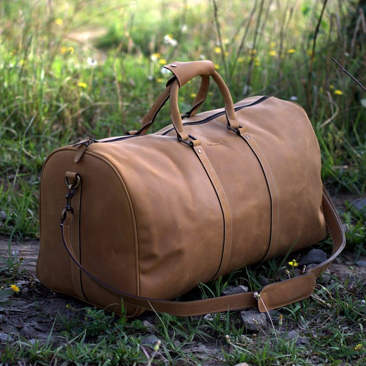 "DIMENSIONS: 12\"H x 23.5\"L x 11\"D Sand Brown Leather Duffel Bag will last you lifetime. Versatile and stylish, this hand made overnight duffle is a timeless classic travel essential. With huge interior, perfect as a weekender or week long trip. This Cabin Luggage is designed using top grain cowhide leather with Crazy Horse finish. Brass Hardware and cotton lining allows this weekender to stay firm and hold on tight for a sweet weekend ride. Inside the handcrafted large duffel, at one end, we Camping Bags, Brown Luggage, Leather Overnight Bag, Leather Holdall, Leather Bag Design, Large Travel Bag, Leather Duffel Bag, Handbags Collection, Leather Weekender Bag