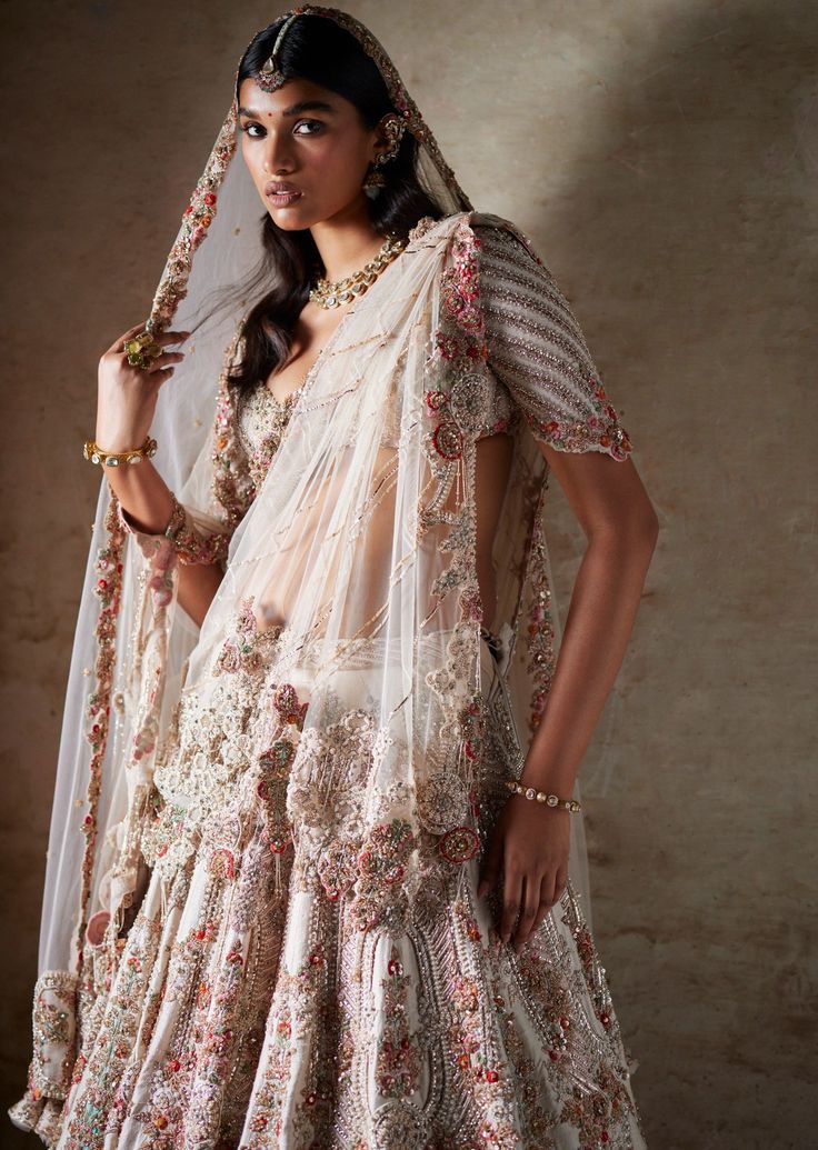 Ivory raw silk bridal lehenga with thread and pearl embroidery paired with two tulle dupattas and an embroidered blouse. Off White Raw Silk Lehenga For Reception, White Chandbali Lehenga With Resham Embroidery, Traditional Drape Raw Silk Lehenga With Pearl Embroidery, Cream Wedding Set With Dupatta, White Raw Silk Gown With Dupatta, Wedding Anarkali Set In Raw Silk With Pearl Embroidery, Cream Raw Silk Lehenga With Zari Work, Cream Lehenga With Intricate Embroidery In Traditional Drape, Raw Silk Lehenga With Intricate Embroidery For Wedding