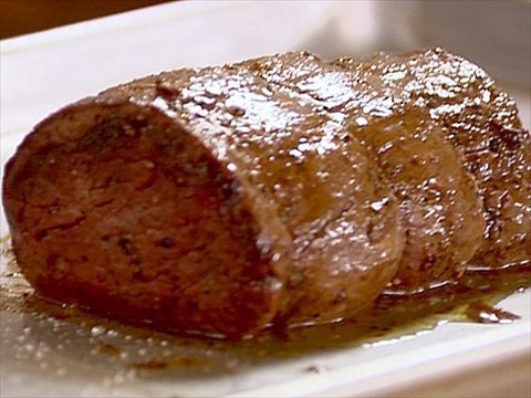 a piece of meat sitting on top of a white plate covered in brown sugar and syrup