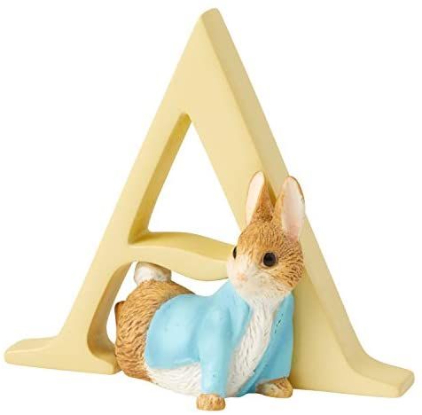 a figurine of a rabbit with a blue shirt on sitting in front of a letter