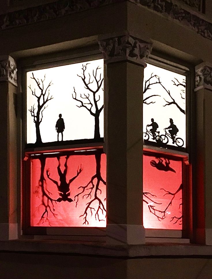 the silhouettes of two people on bicycles are seen through an illuminated window