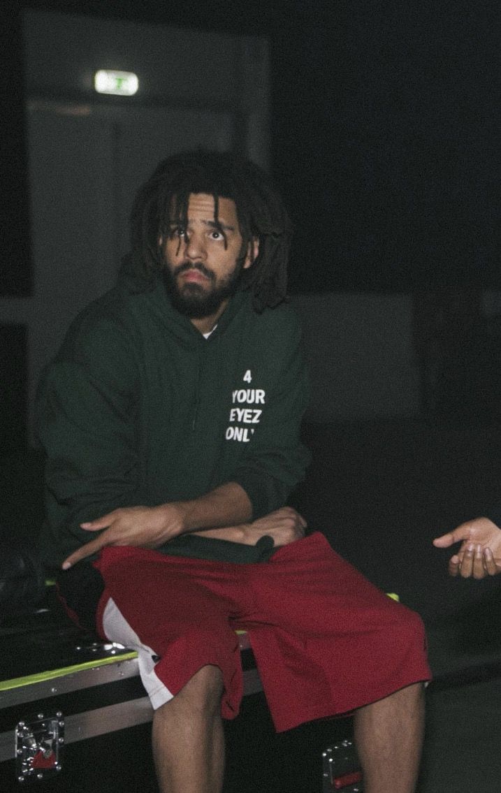 a man with dreadlocks sitting on top of a luggage bag in the dark