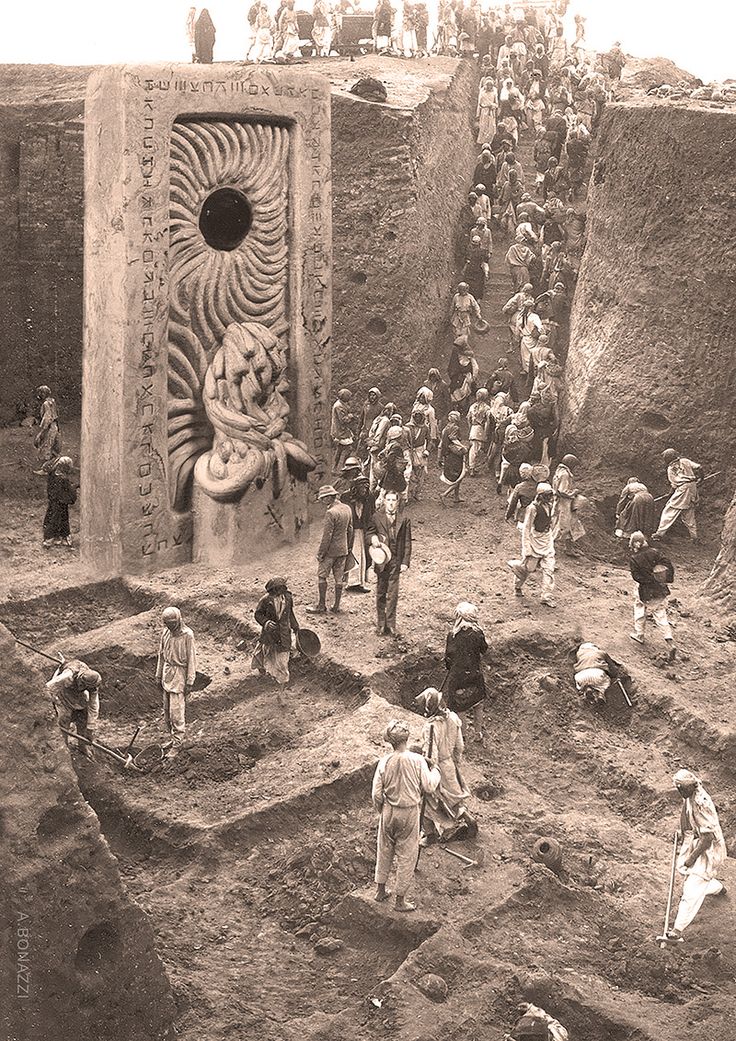 an old black and white photo of people working in the mud with a statue behind them