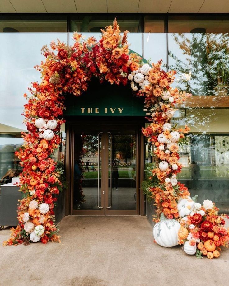 an orange and white floral arch is in front of the entrance to the ivy hotel