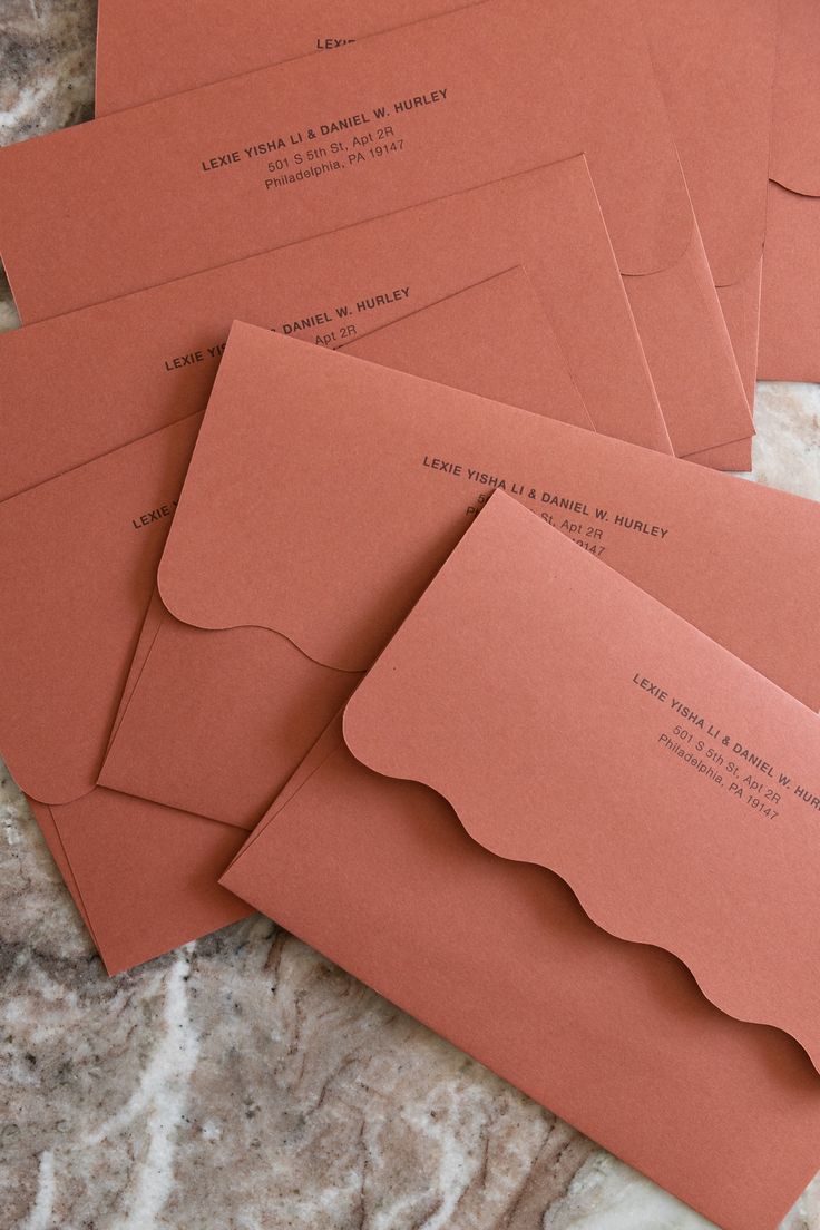 four envelopes with red paper on them sitting on a marble counter top next to each other