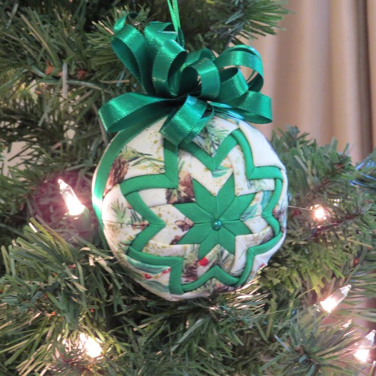 an ornament hanging from a christmas tree with green ribbon and bow on it