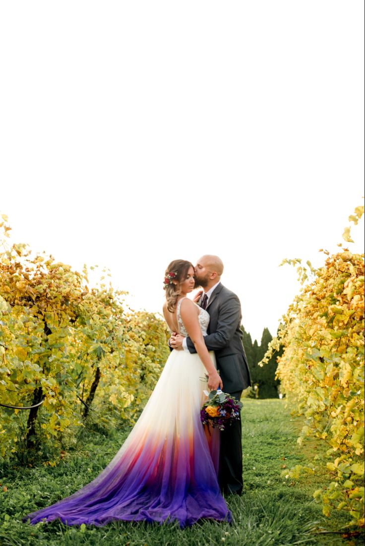 a bride and groom standing in the middle of a field surrounded by yellow vines at their wedding