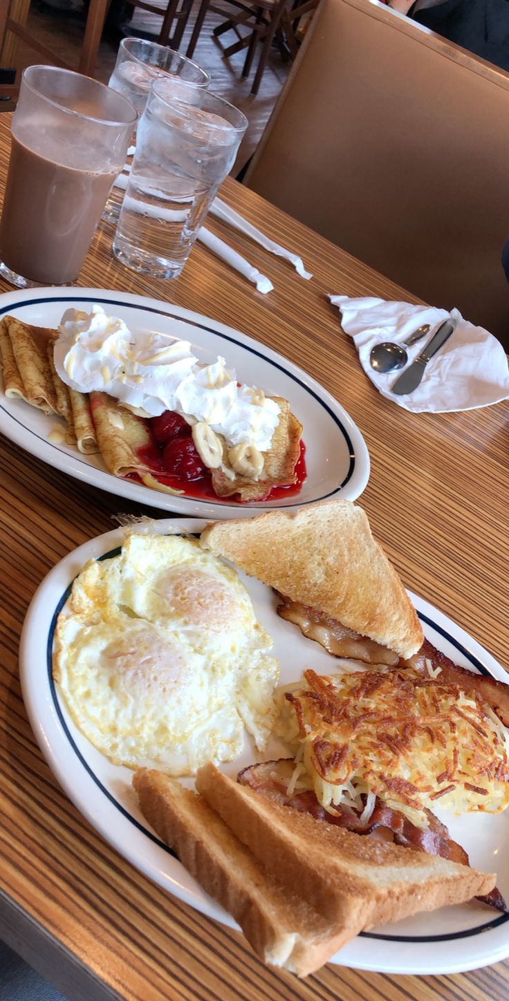 two white plates topped with breakfast foods on top of a wooden table