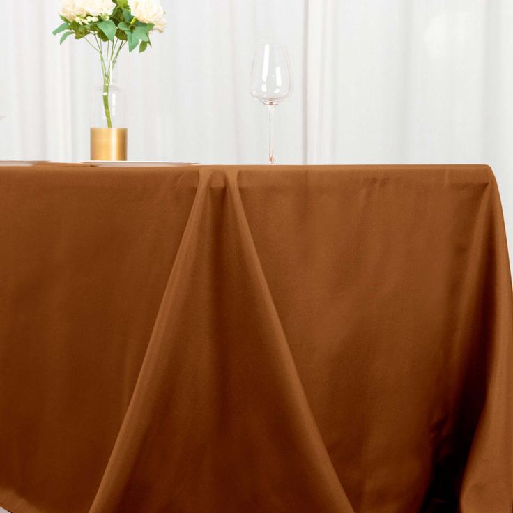 a table with a brown cloth draped over it and a vase filled with flowers on top