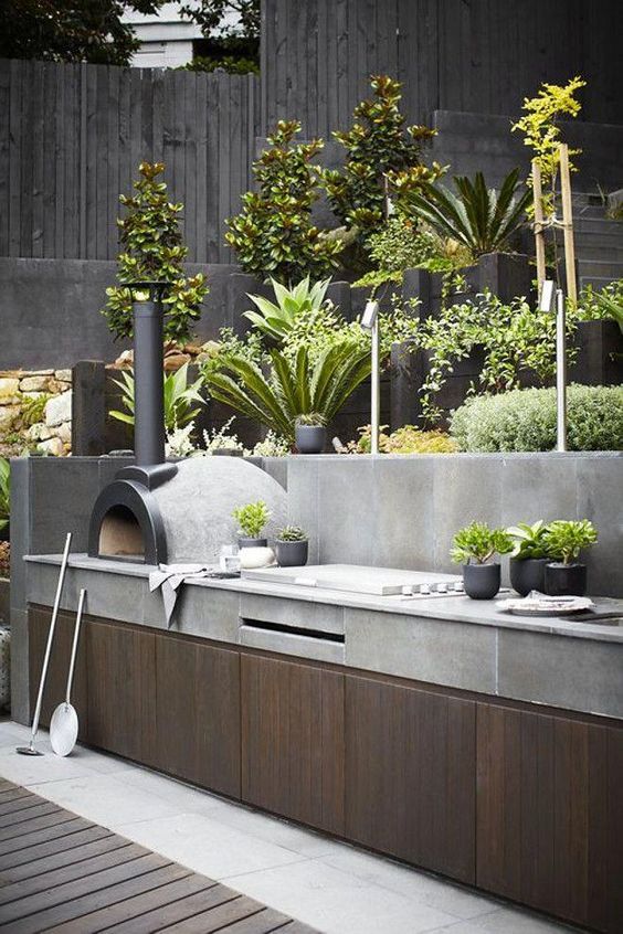 an outdoor kitchen with potted plants on the counter