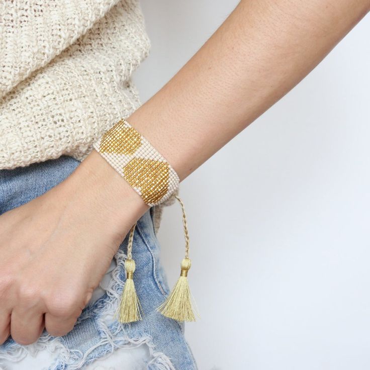 a close up of a person wearing a bracelet with tassels on their wrist