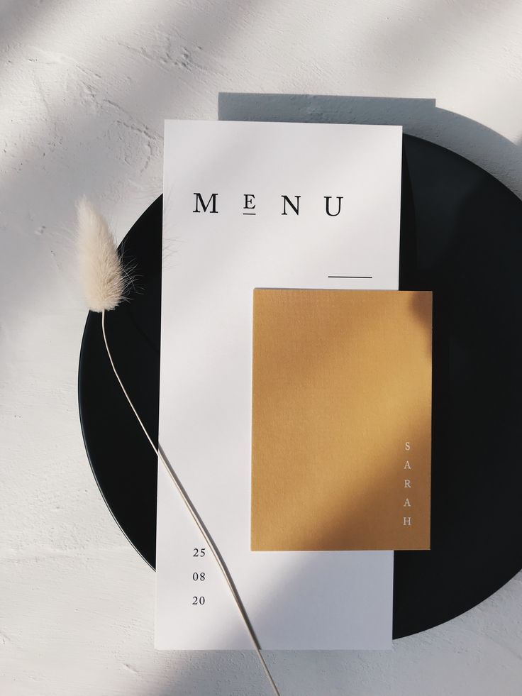 a black plate topped with a piece of paper next to a white and brown object