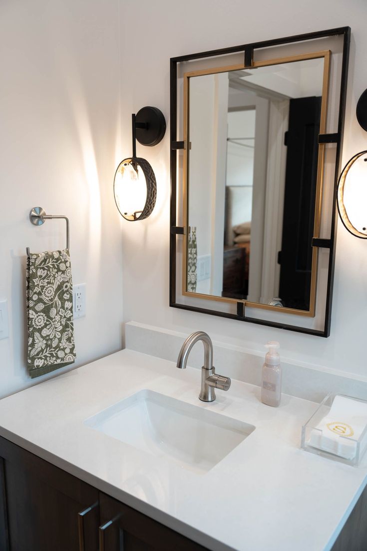 a bathroom with a sink, mirror and towel rack in it's center area