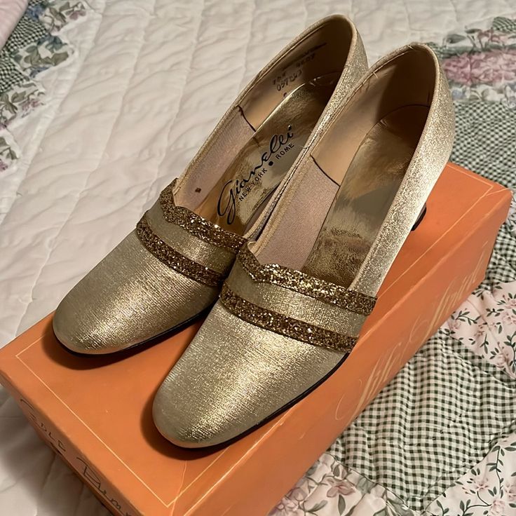 a pair of gold shoes sitting on top of an orange box